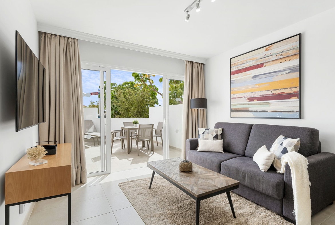 Modern living area with a sofa, wall art, and access to a bright terrace in a Golf del Sur investment property