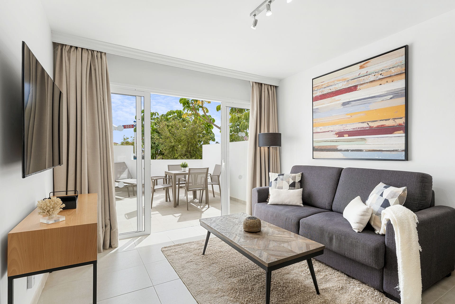 Modern living area with a sofa, wall art, and access to a bright terrace in a Golf del Sur investment property