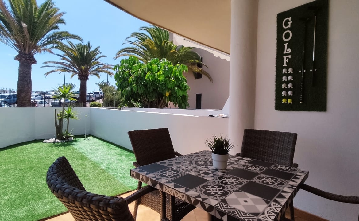 Spacious terrace with outdoor dining area and golf-themed decor, surrounded by palm trees and a view of the garden